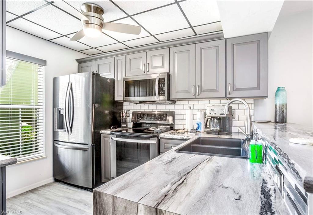 Modern kitchen featuring light gray cabinetry, stainless steel appliances, a subway tile backsplash, and a large single-basin sink
