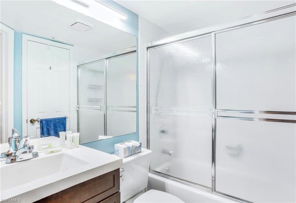 Full bathroom featuring a vanity with a white countertop and integrated sink, a chrome faucet, and a large wall-mounted mirror