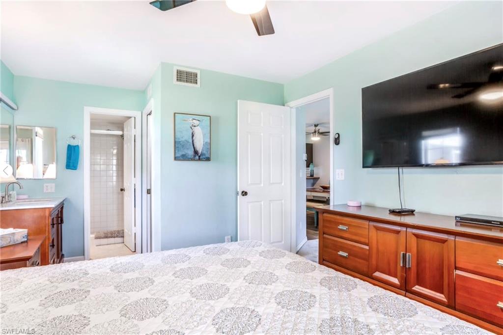 Light-colored walls featuring a ceiling fan, wood-finish dresser, and a large wall-mounted screen