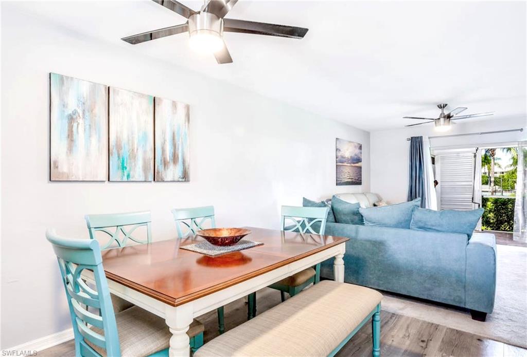 Open-concept living space featuring wood-finish flooring, white walls, and two ceiling fans with integrated lighting