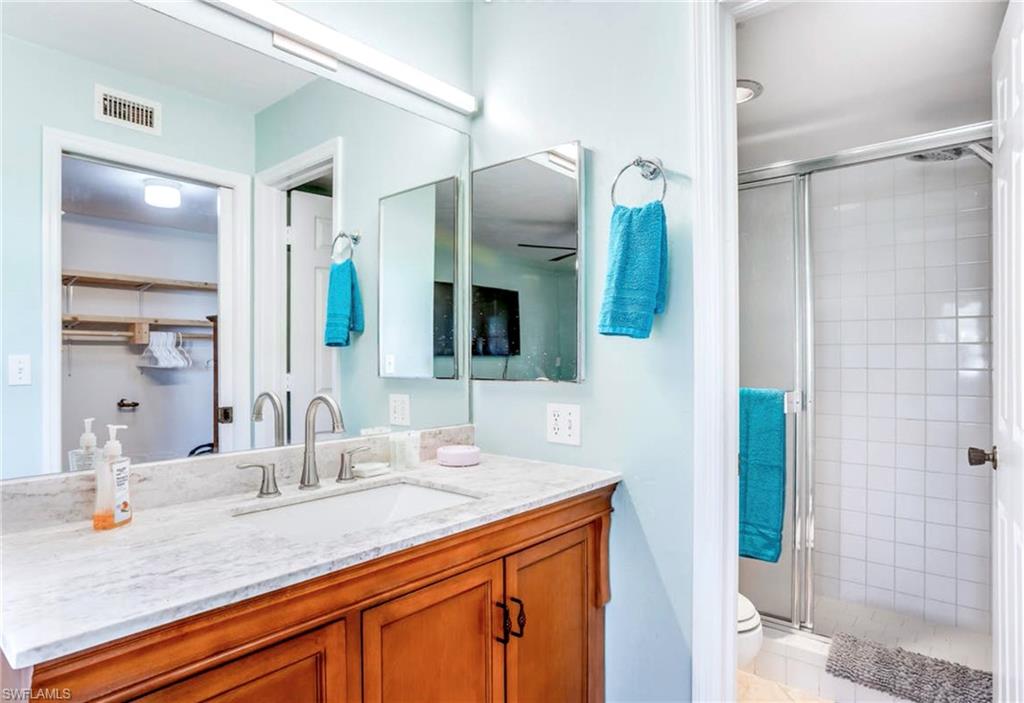 Bathroom vanity with a light-toned countertop, integrated sink, and brushed nickel faucet