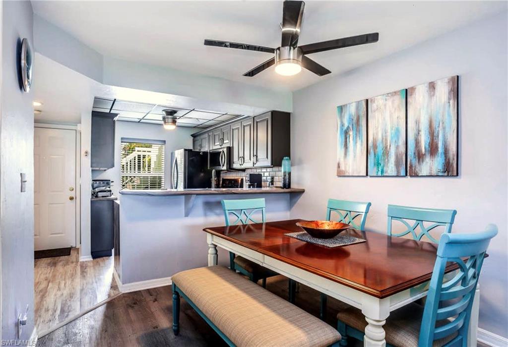 Dining area featuring wood-finish flooring, a contemporary ceiling fan, and a pass-through opening to the kitchen