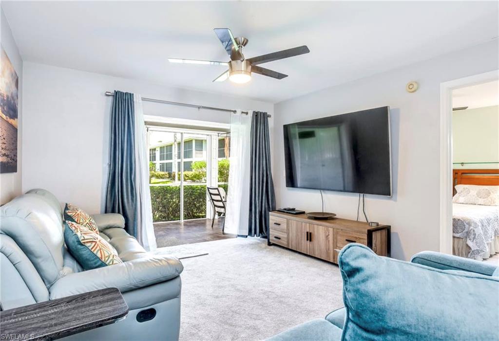 Living area featuring light gray walls and a ceiling fan with integrated lighting
