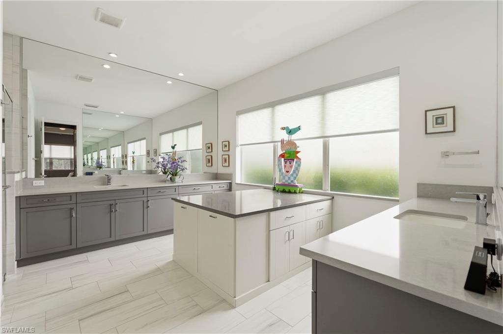 Large primary bathroom suite with dual counters, walk-in shower, storage area with built-in laundry baskets.
