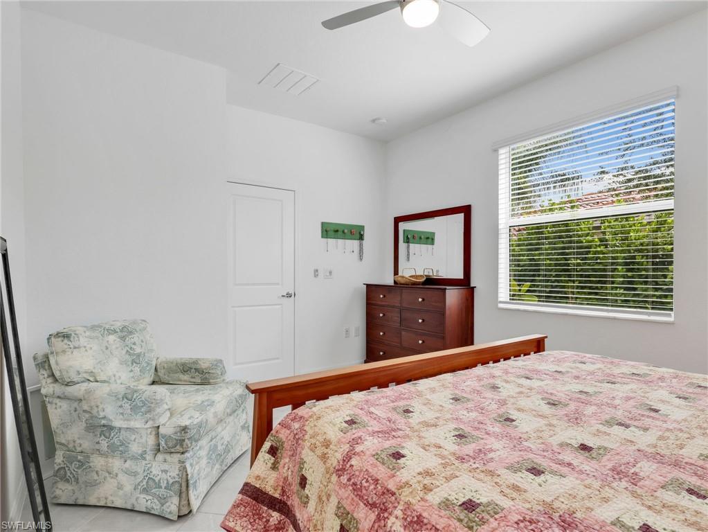 Bright room featuring a large window with blinds, a ceiling fan with light, and white interior door