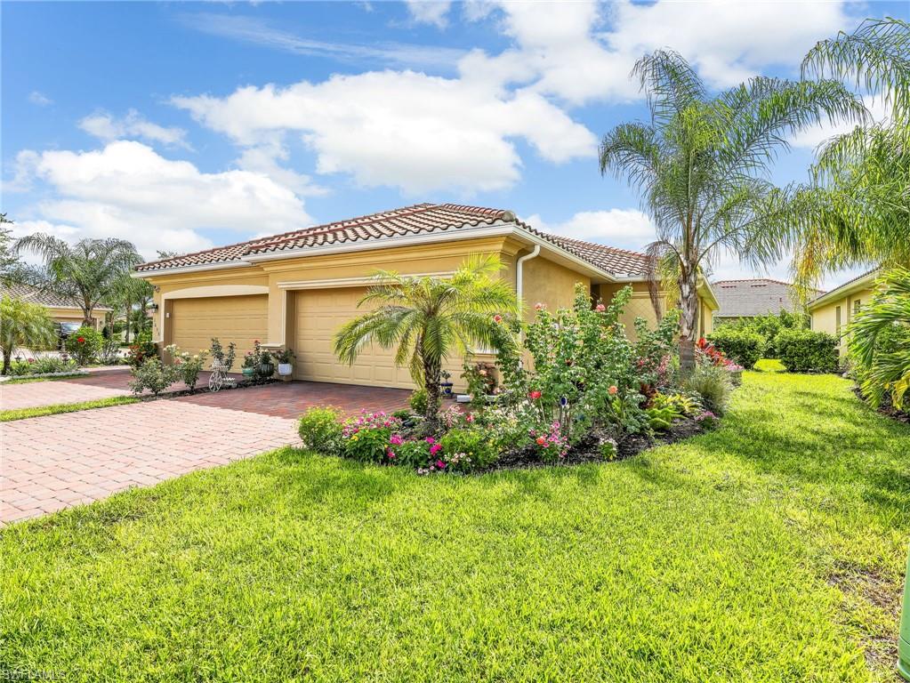 Stucco exterior with a tiled roof, featuring a brick paver driveway and a two-car garage