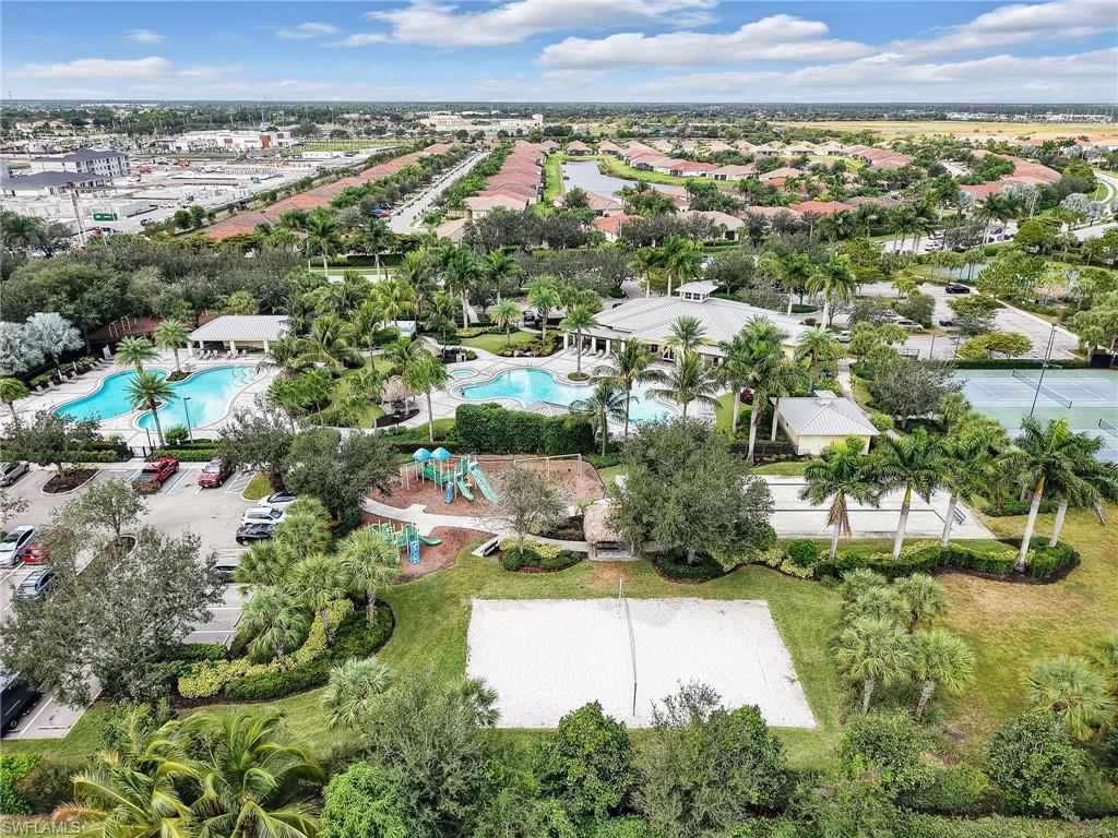 Aerial perspective showcasing community amenities, including multiple swimming pools, tennis courts, a sand volleyball court, and a playground surrounded by mature landscaping