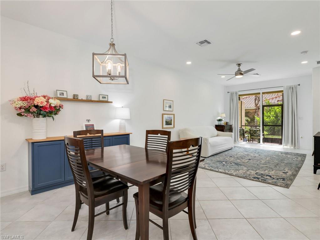 Open-concept living space featuring neutral tile flooring, a dining area with a wood-finish table, and a built-in blue cabinetry buffet with a wood countertop