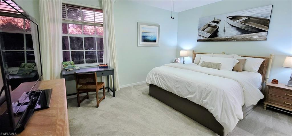King bed in guest bedroom with TV and desk