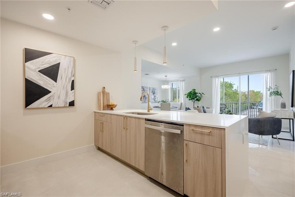 Kitchen with a peninsula, stainless steel dishwasher, light brown cabinetry, open floor plan, and light countertops