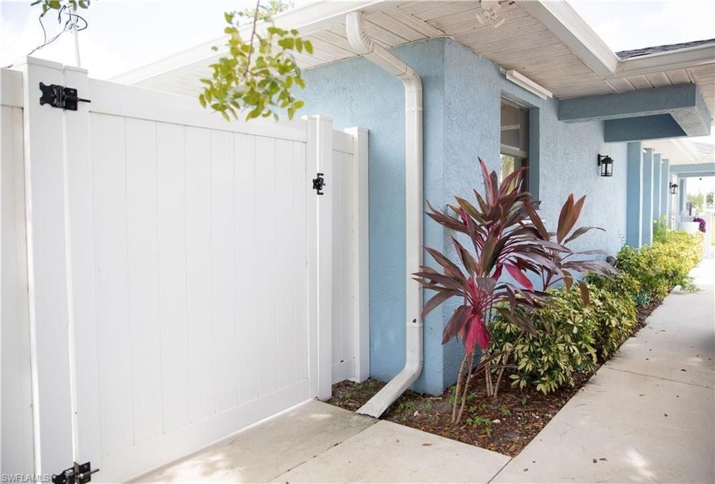 White privacy gate with black hardware, complementing the blue stucco exterior