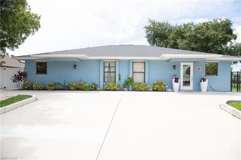 Light blue stucco exterior with a dark shingle roof
