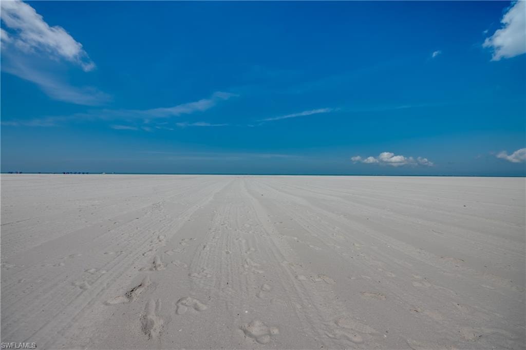 Expansive white sand beach under a clear blue sky with minimal cloud cover