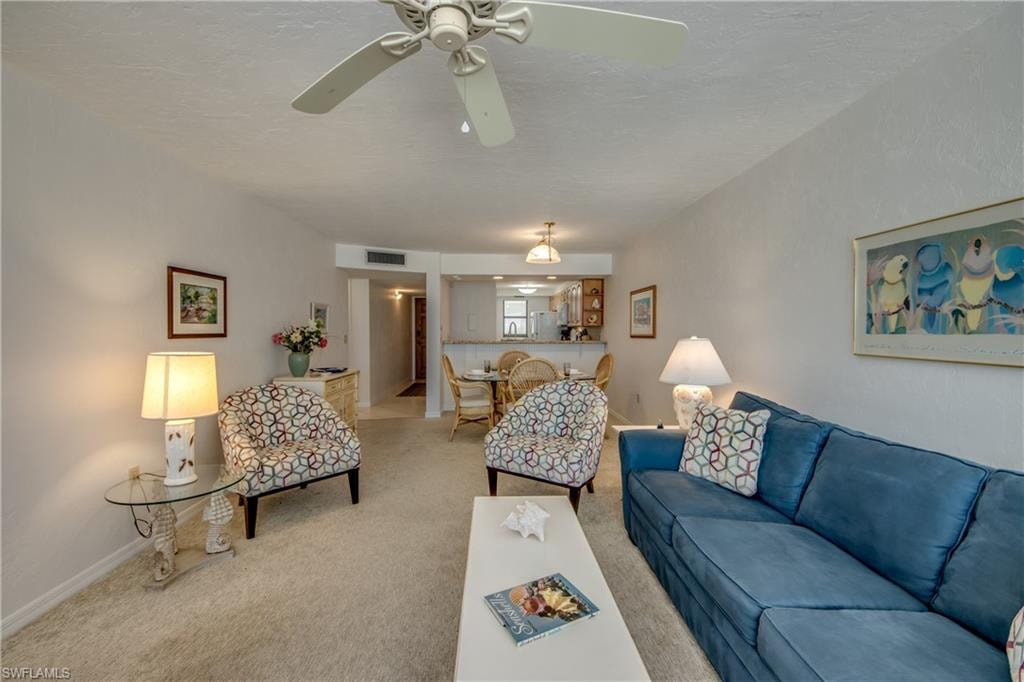 Open concept living area featuring textured ceilings, neutral carpeting, and a ceiling fan