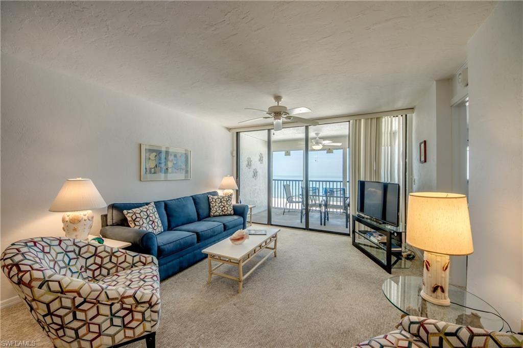 Living area featuring direct patio access, ocean scenery, ceiling fan, and carpet flooring