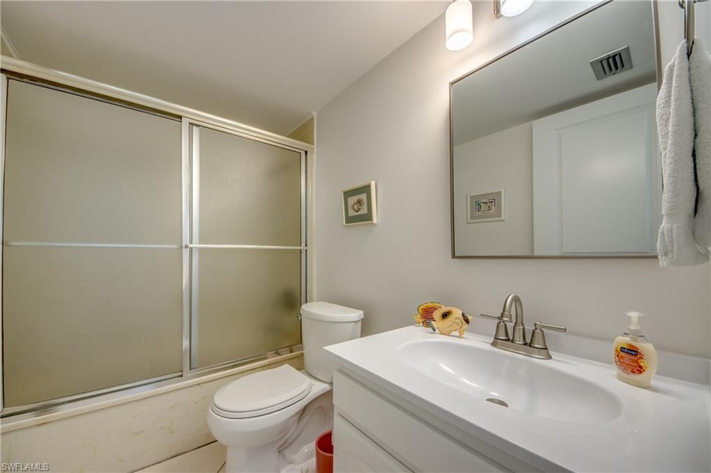 Bathroom featuring a shower-tub combination with frosted sliding doors, a single-sink vanity with a white countertop, and an integrated rectangular basin