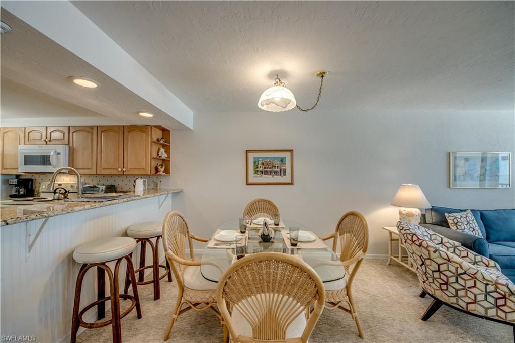 Open concept dining area featuring a glass-top table, woven chairs, and a pendant light fixture