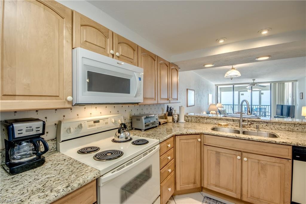 Kitchen featuring wood-finish cabinetry, speckled countertops, a double basin sink with a high-arc faucet, and an over-the-range microwave