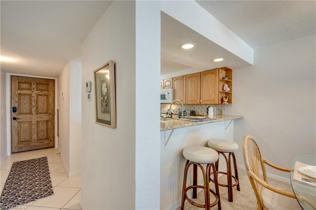 Kitchen with wood-finish cabinetry, recessed lighting, and a granite countertop breakfast bar