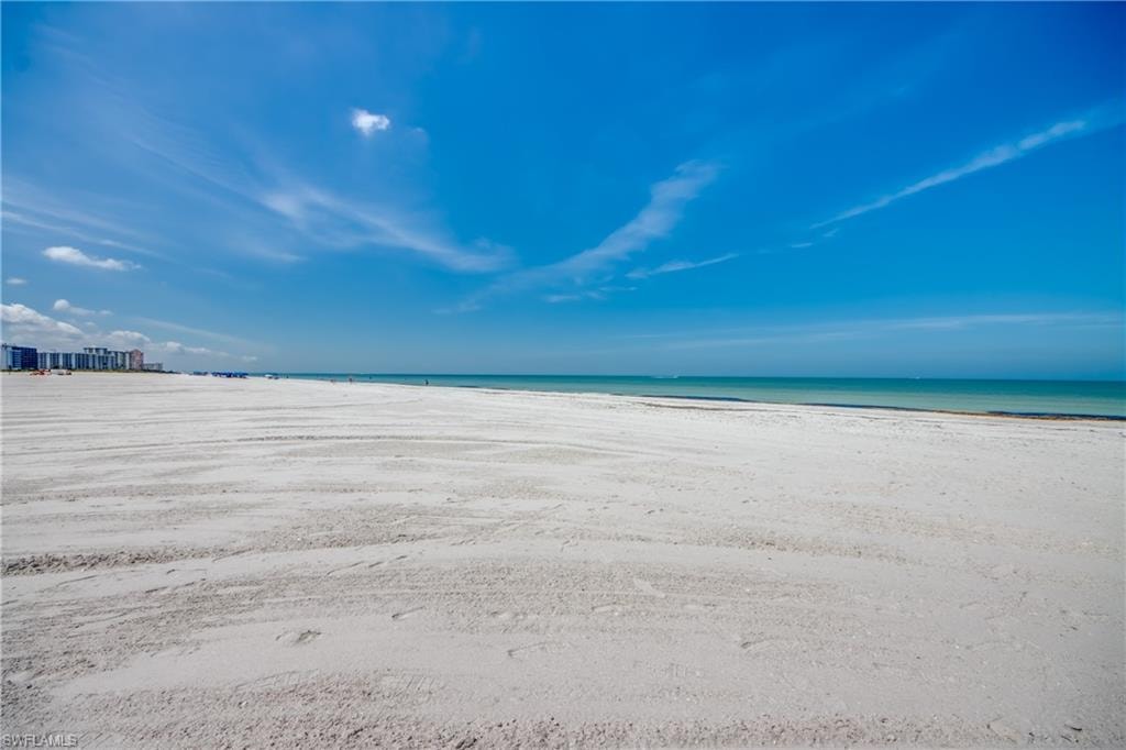 Expansive white sand beach with turquoise waters and a distant skyline