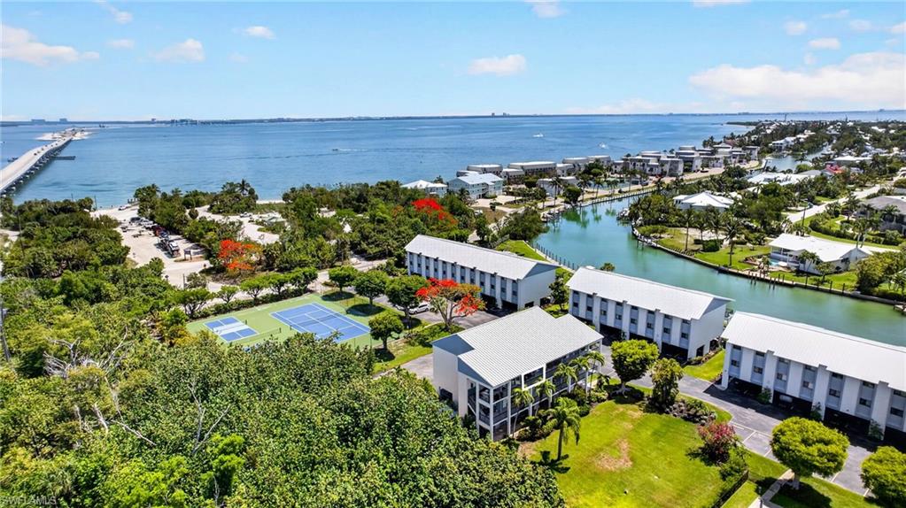 Waterfront community with multiple buildings, recreational courts, and a bridge in the distance