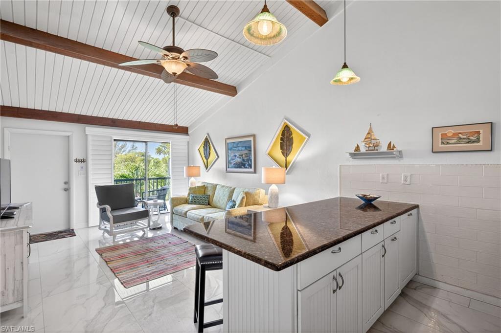 Vaulted ceiling with exposed wood beams, bright white shiplap, and a ceiling fan