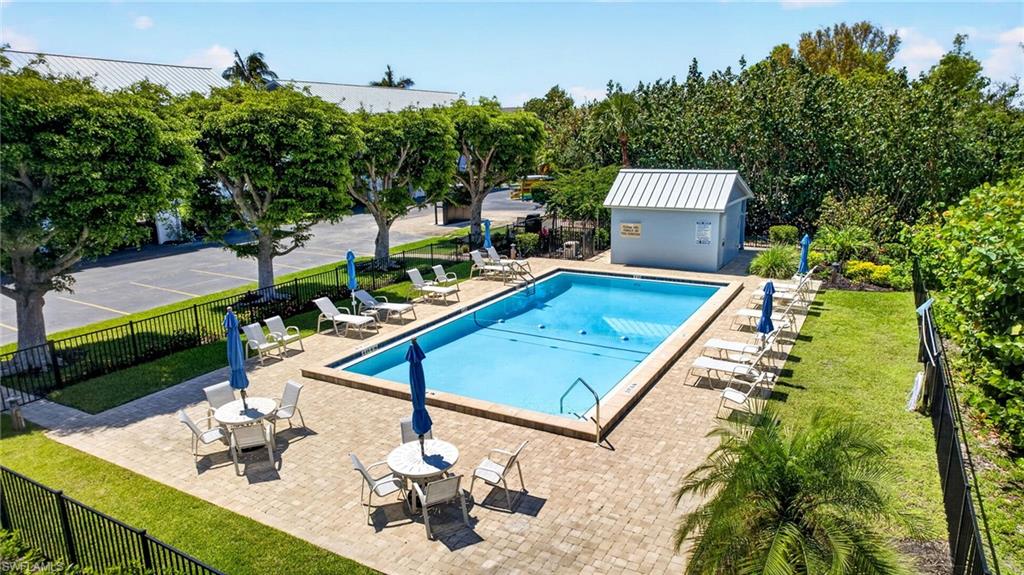 Rectangular outdoor swimming pool featuring a paver deck surround, dedicated pool house with a metal roof, and lush perimeter landscaping