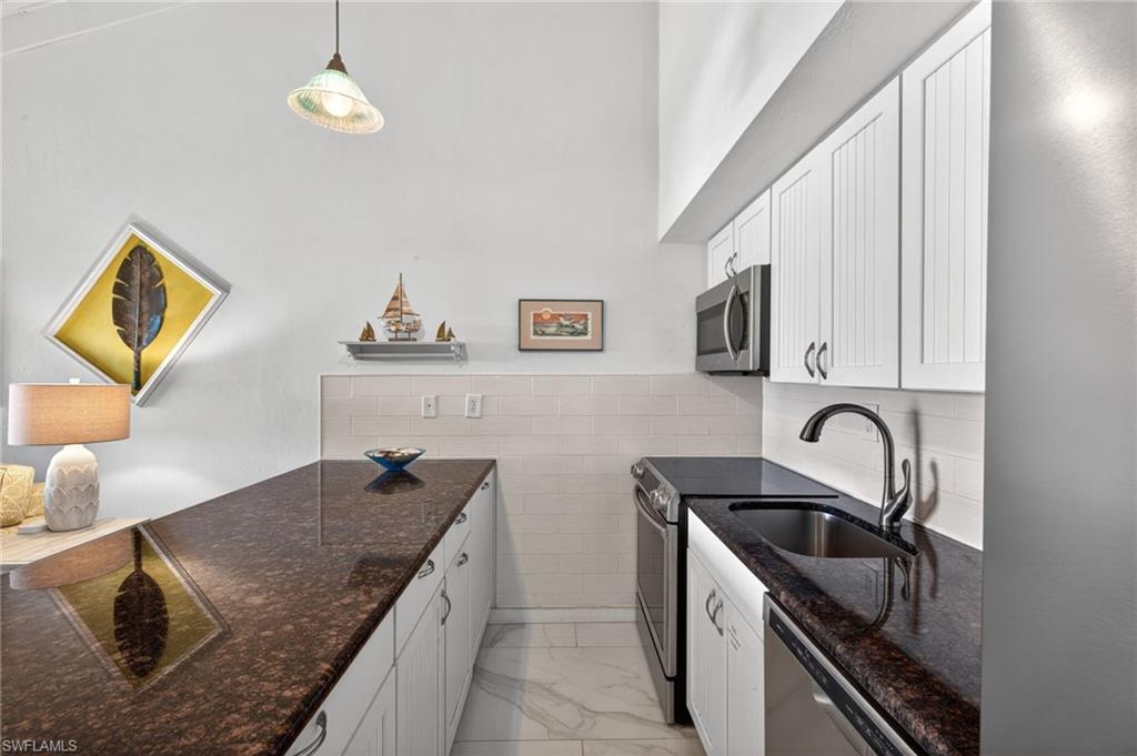 Kitchenette featuring white beadboard cabinetry, dark speckled countertops, and a white subway tile backsplash