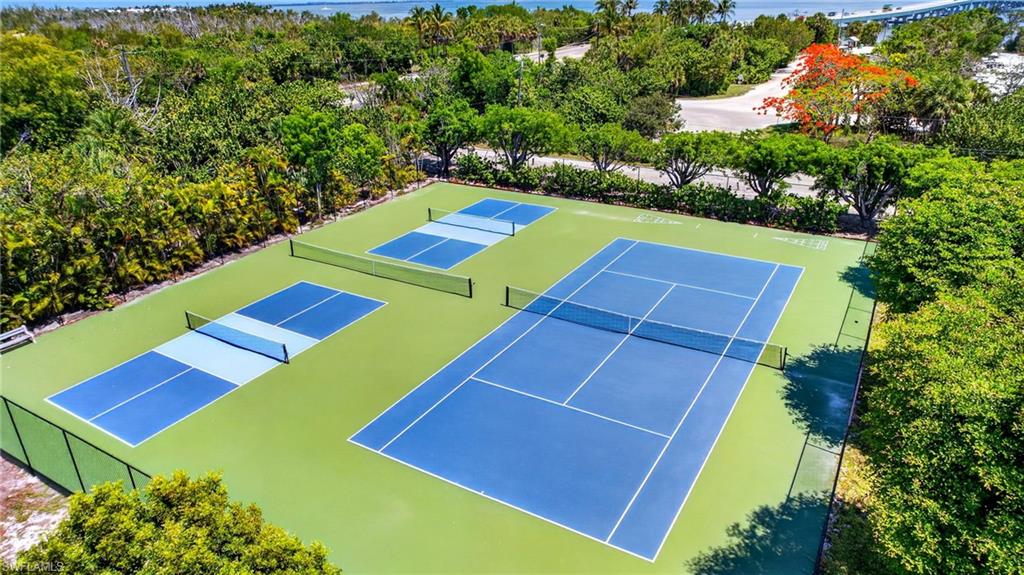 Outdoor recreational area featuring a full-size tennis court and multiple pickleball courts