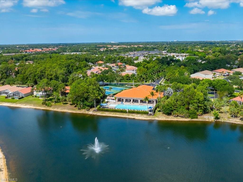 Waterfront community with a large pool deck, multiple tennis courts, and a central clubhouse with a terracotta tile roof