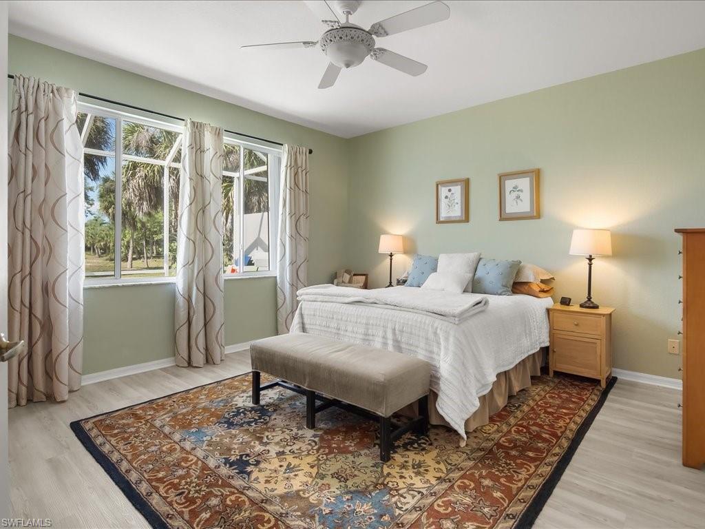 Spacious room featuring multiple windows, a ceiling fan, and light wood-finish flooring