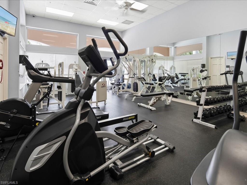Fitness center featuring multiple exercise machines, weight racks, large wall mirrors, and recessed lighting