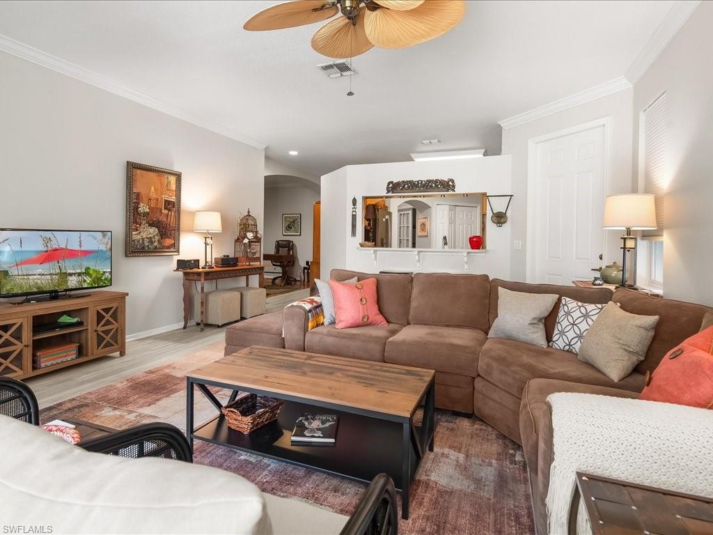 Spacious living area featuring light wood-finish flooring and crown molding