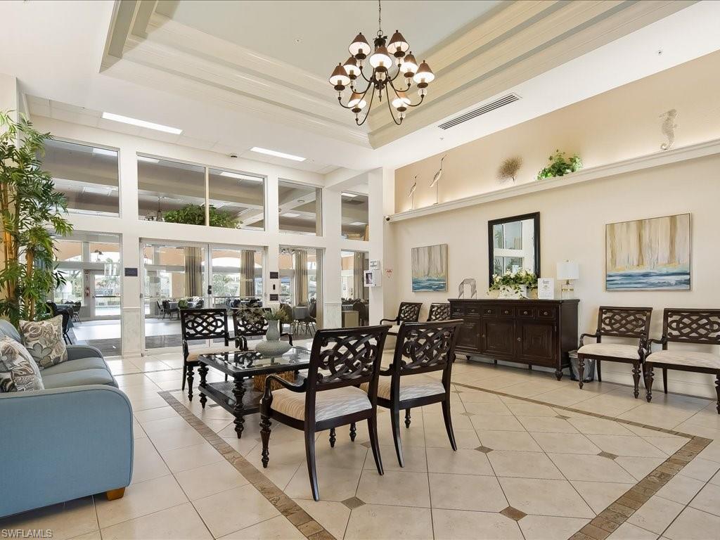 Spacious interior featuring a coffered ceiling with a chandelier, extensive window walls, and tiled flooring with decorative inlays