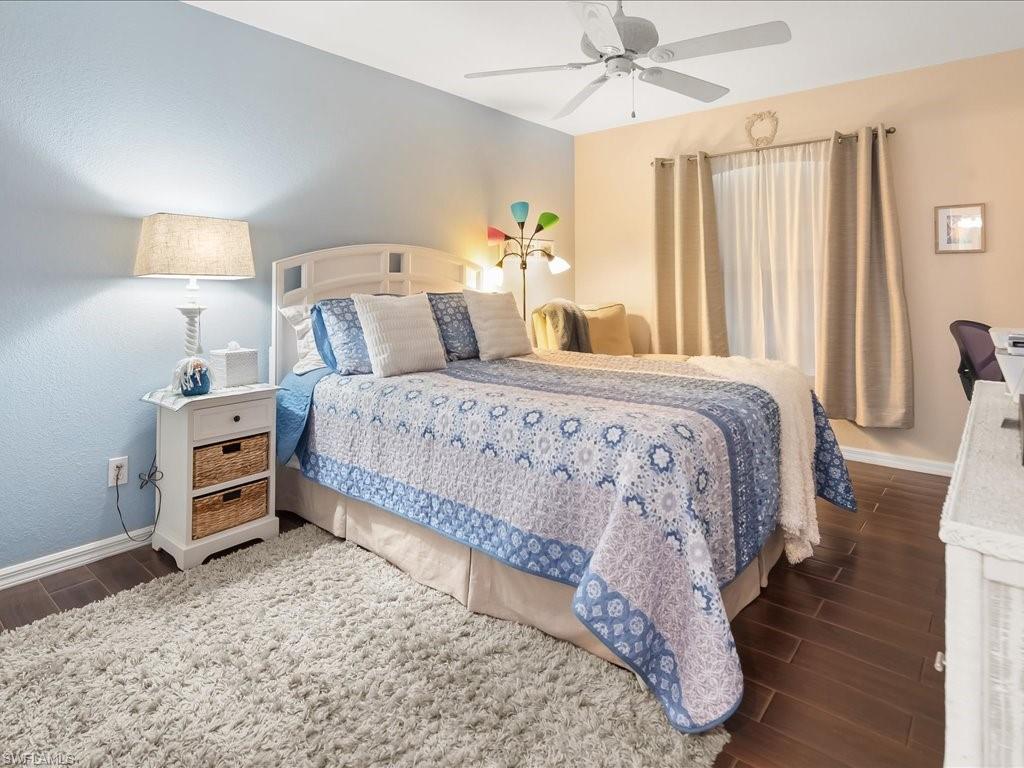 Bedroom featuring wood-finish flooring, a ceiling fan, and a window with curtains