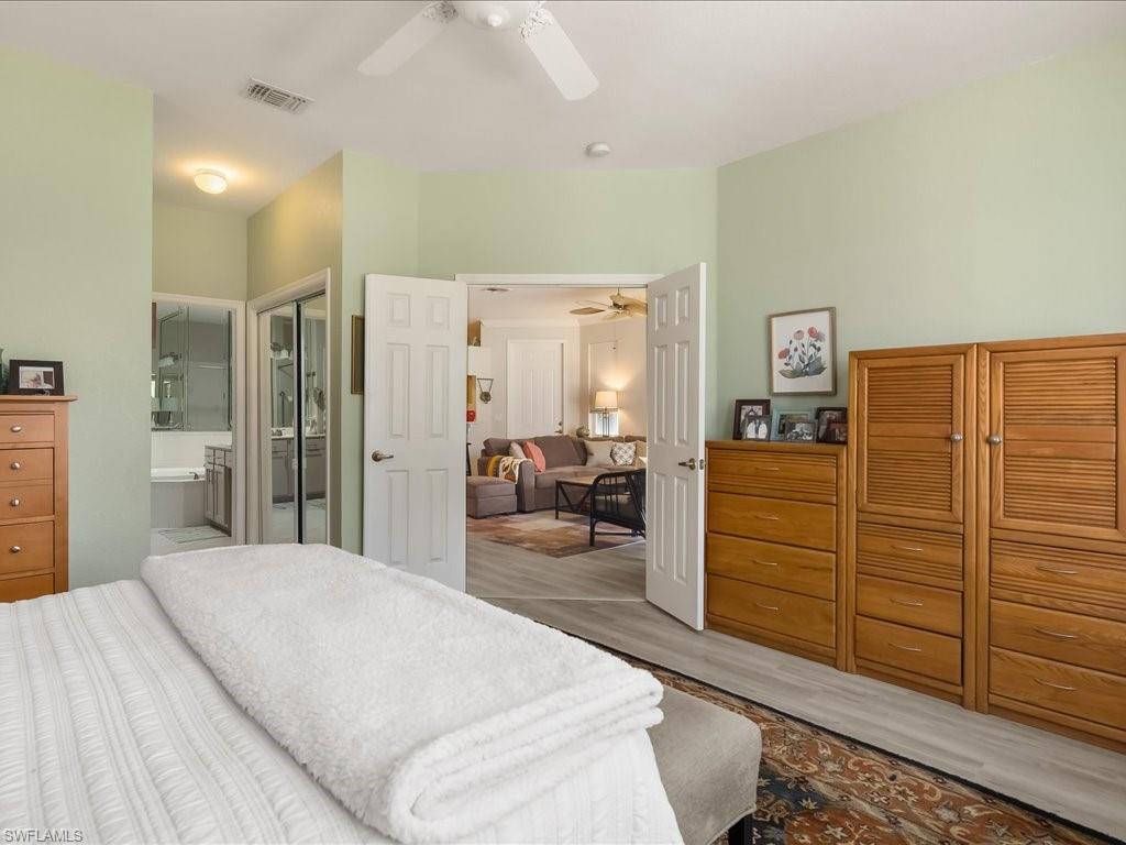 Spacious bedroom featuring light-toned walls and wood-finish flooring