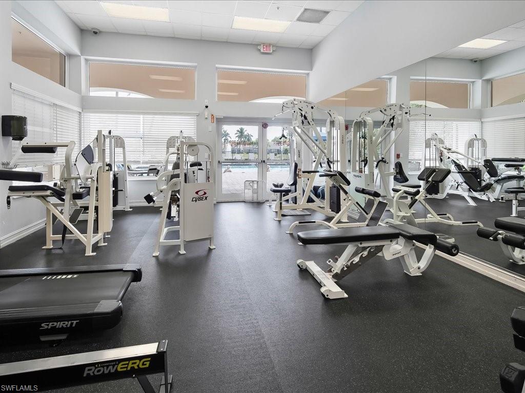 Fitness center featuring a variety of exercise equipment, full-height mirrored walls, and large windows with horizontal blinds