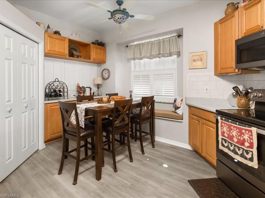 Kitchen featuring wood-finish flooring, light wood cabinetry, white subway tile backsplash, and a built-in window seat with plantation shutters