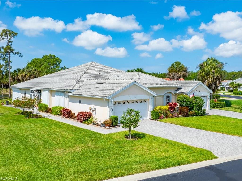 Exterior featuring a tile roof, stucco finish, paver driveway, and manicured landscaping