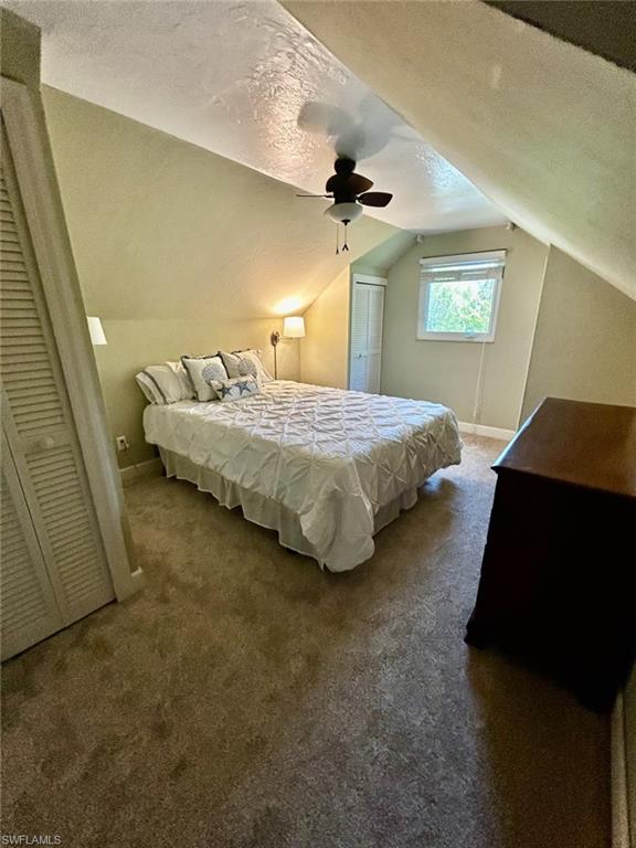 Carpeted room featuring a sloped ceiling, ceiling fan, and a window with blinds