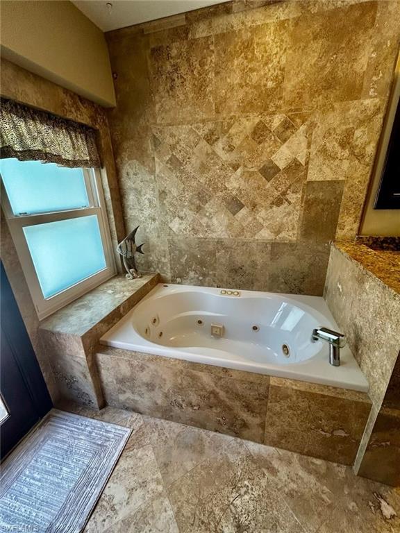 Jetted soaking tub set within a tiled surround, complemented by full-height tile walls and coordinated tile flooring
