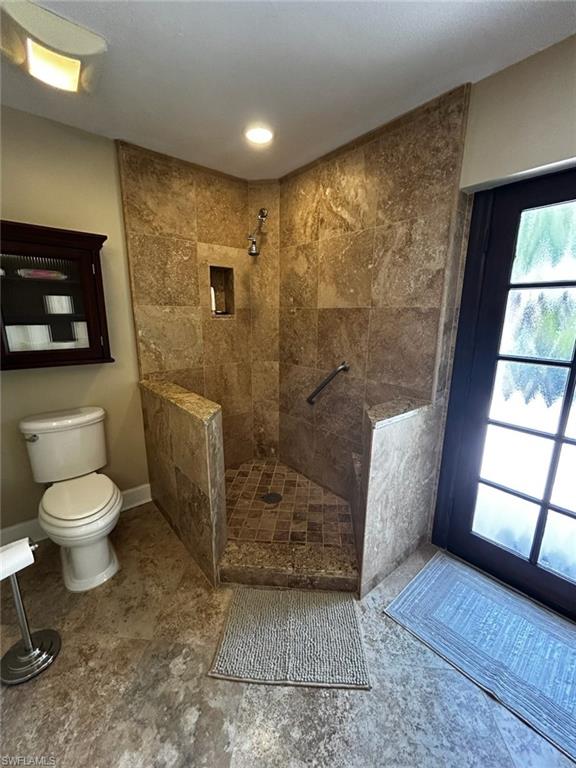 Corner walk-in shower with full-height stone-look tile surround and mosaic tile floor