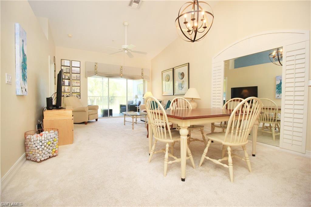 Carpeted dining room featuring ceiling fan with notable chandelier and vaulted ceiling
