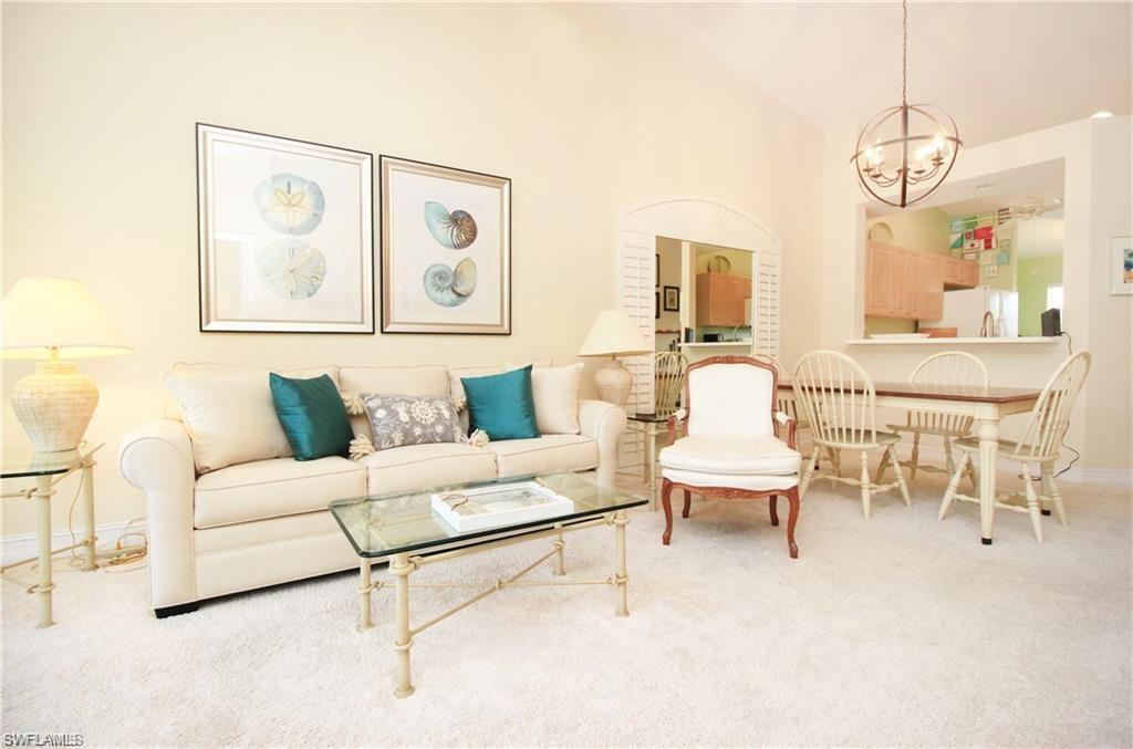 Living room featuring lofted ceiling, an inviting chandelier, and carpet floors