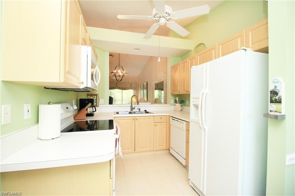 Kitchen with pendant lighting, ceiling fan with notable chandelier, white appliances, sink, and light brown cabinets