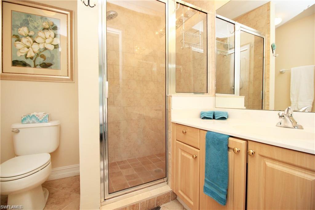 Bathroom with a shower with door, vanity, toilet, and tile patterned floors