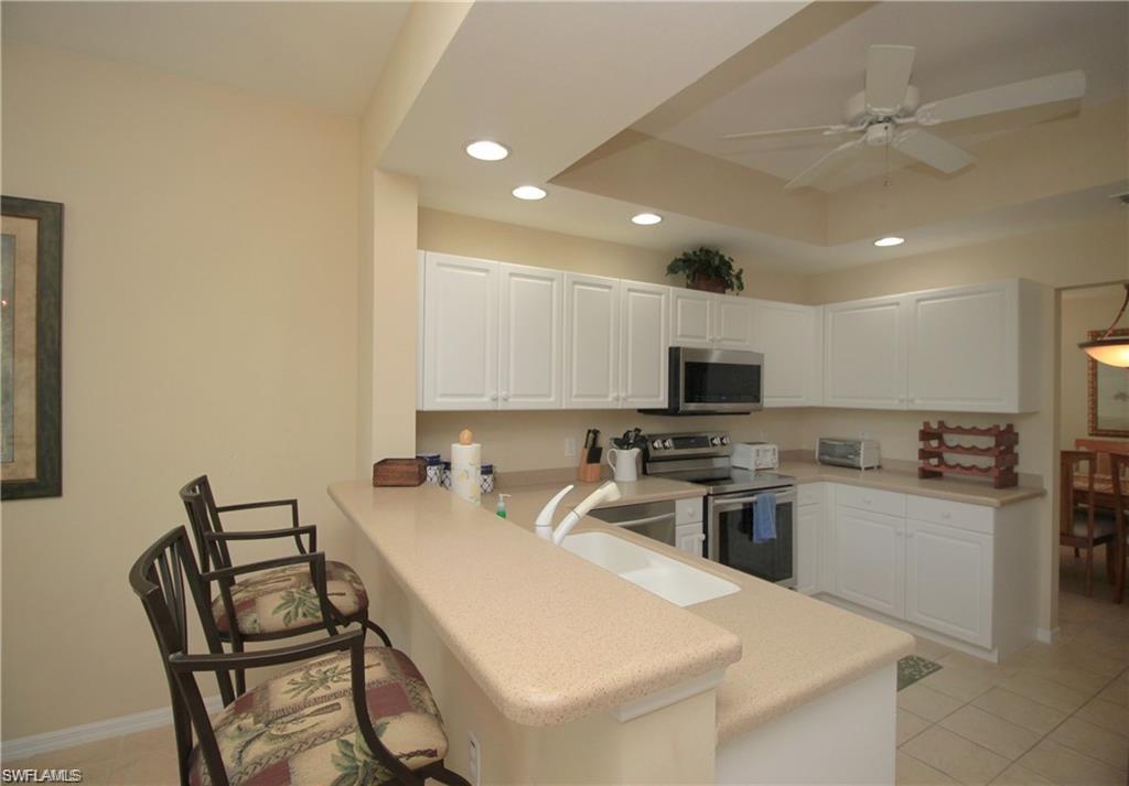 Kitchen with white cabinets, appliances with stainless steel finishes, kitchen peninsula, and ceiling fan