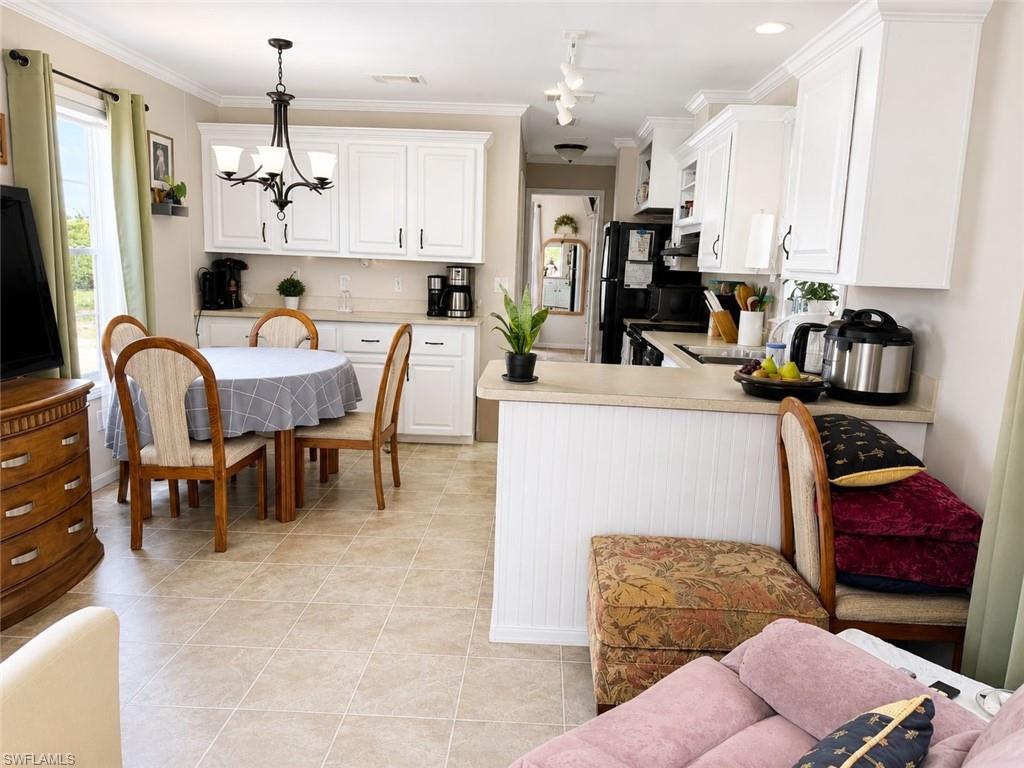 Bright kitchen and dining area featuring white cabinetry, light-toned countertops, and tile flooring
