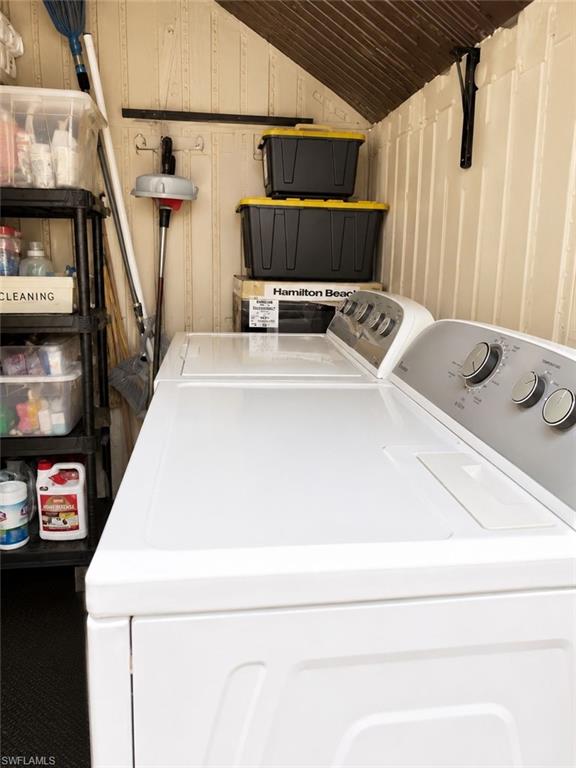Utility area featuring a top-load washing machine, textured white panel walls, and a corrugated metal ceiling