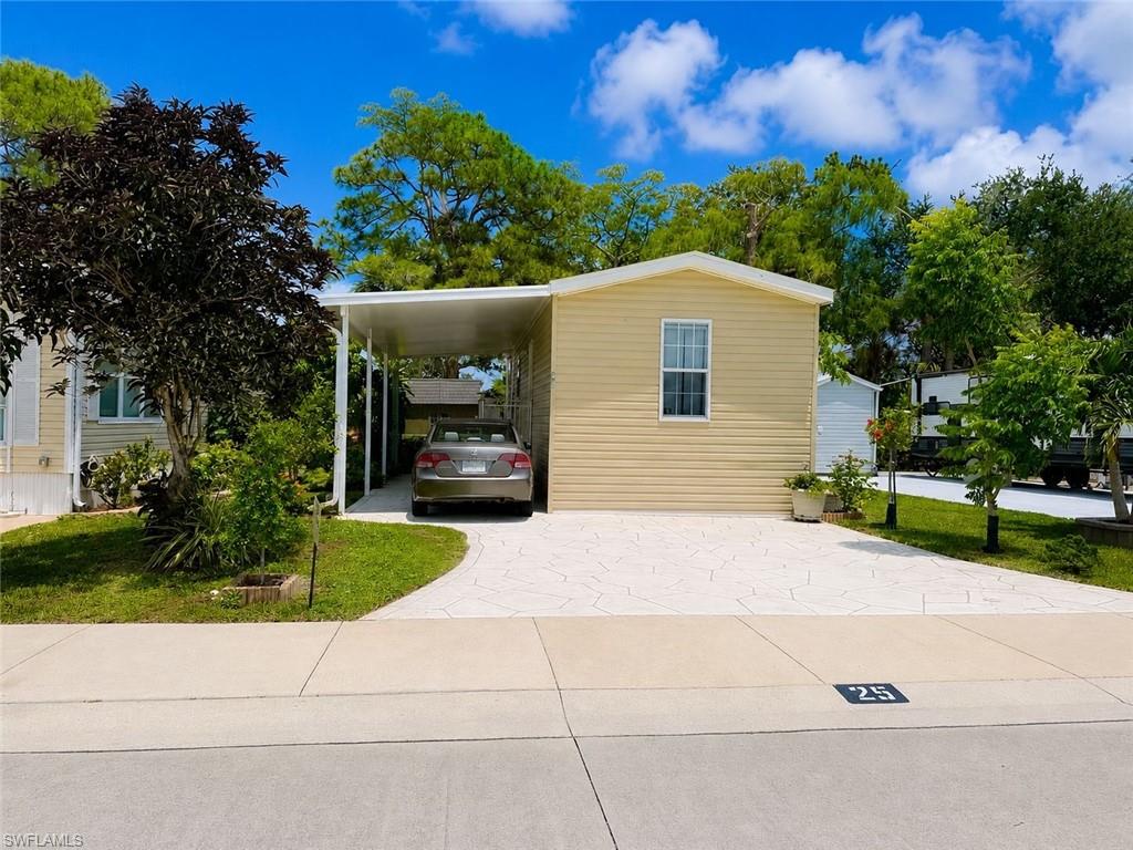Single-story residence featuring light yellow siding, white trim, and a white carport